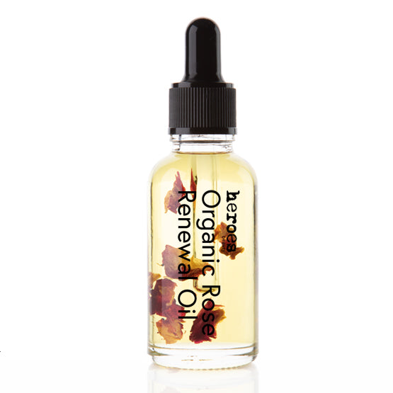 Image of our Organic Rose Renewal oil in a 1 ounce clear bottle with black dropper lid and rose petals floating in a golden elixer of essential oils. 
